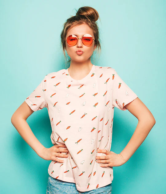 Woman wearing a t-shirt with carrot pattern and sunglasses against a light blue background